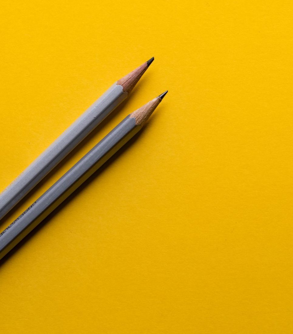 Two pencils artfully arranged on yellow background
